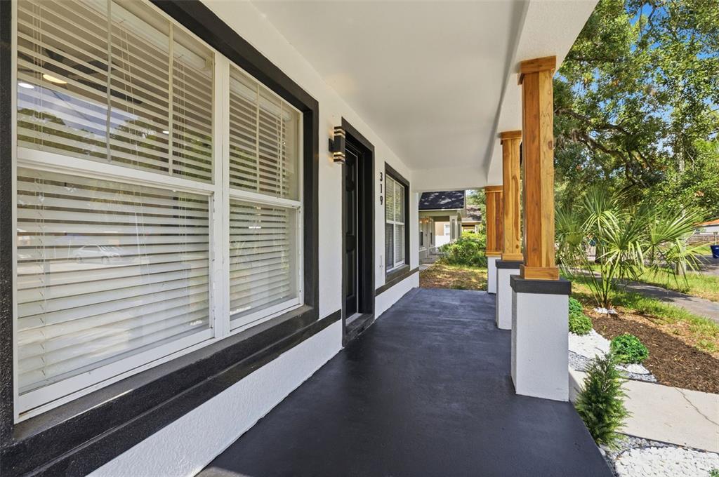 A covered front porch features a black floor, white walls, and wooden support columns — 319 E HANLON STREET, TAMPA, FL