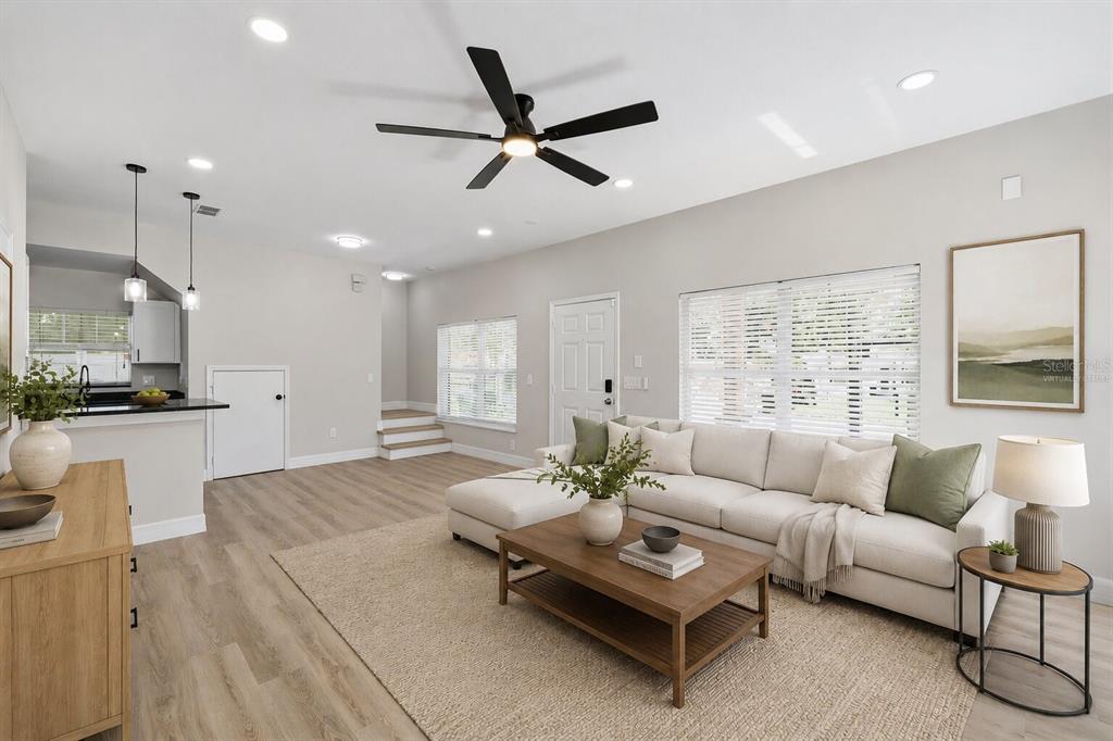 A living room with light wood flooring, a sectional sofa, and a ceiling fan — 319 E HANLON STREET, TAMPA, FL