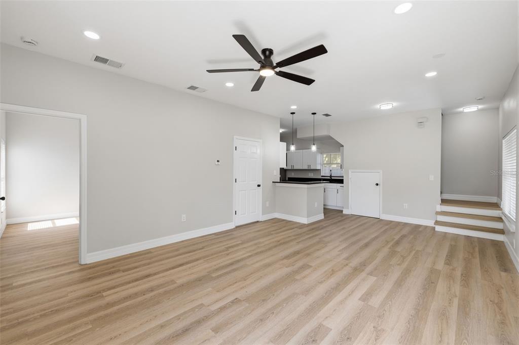An open-concept living area features light wood-look flooring, a ceiling fan, and a kitchen nook — 319 E HANLON STREET, TAMPA, FL