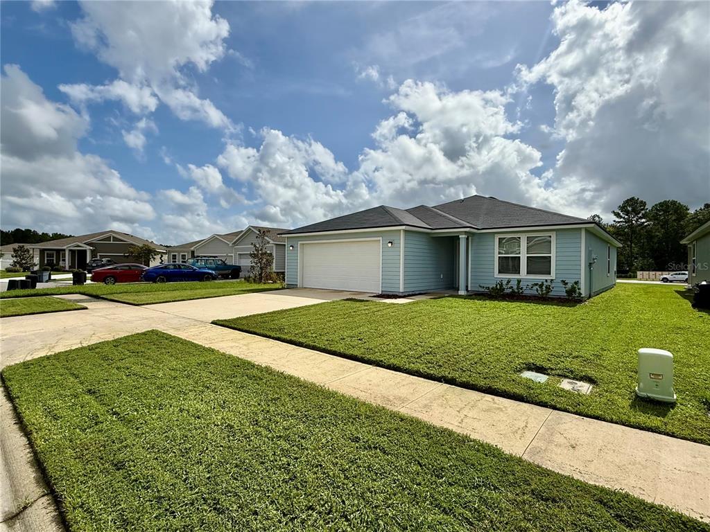 A light blue single-story house with a two-car garage and a green lawn — 1127 GRAND CYPRESS COURT, JACKSONVILLE, FL
