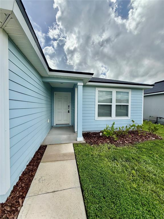 A light blue house exterior features a white front door, a concrete walkway, and landscaping — 1127 GRAND CYPRESS COURT, JACKSONVILLE, FL