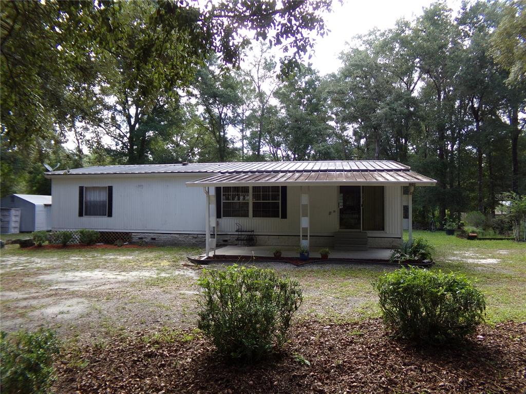 A single-story manufactured home with a metal roof and a front porch sits on a lot — 12199 SW 44TH DRIVE, WEBSTER, FL