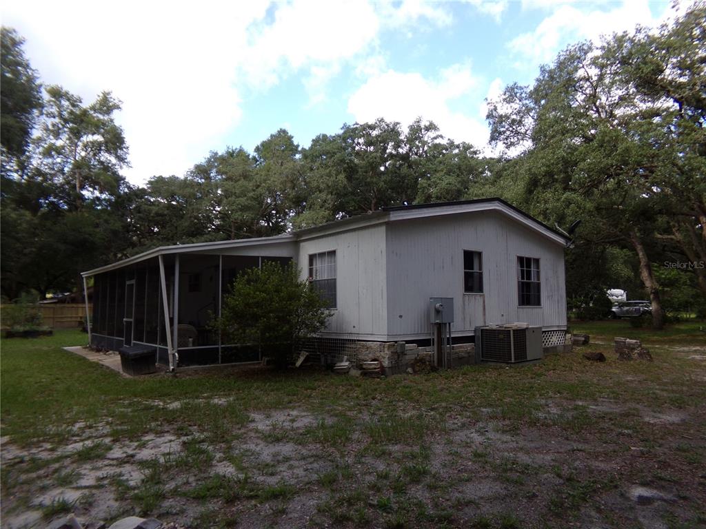 A single-story manufactured home with a screened-in porch and light-colored siding sits on a lot — 12199 SW 44TH DRIVE, WEBSTER, FL
