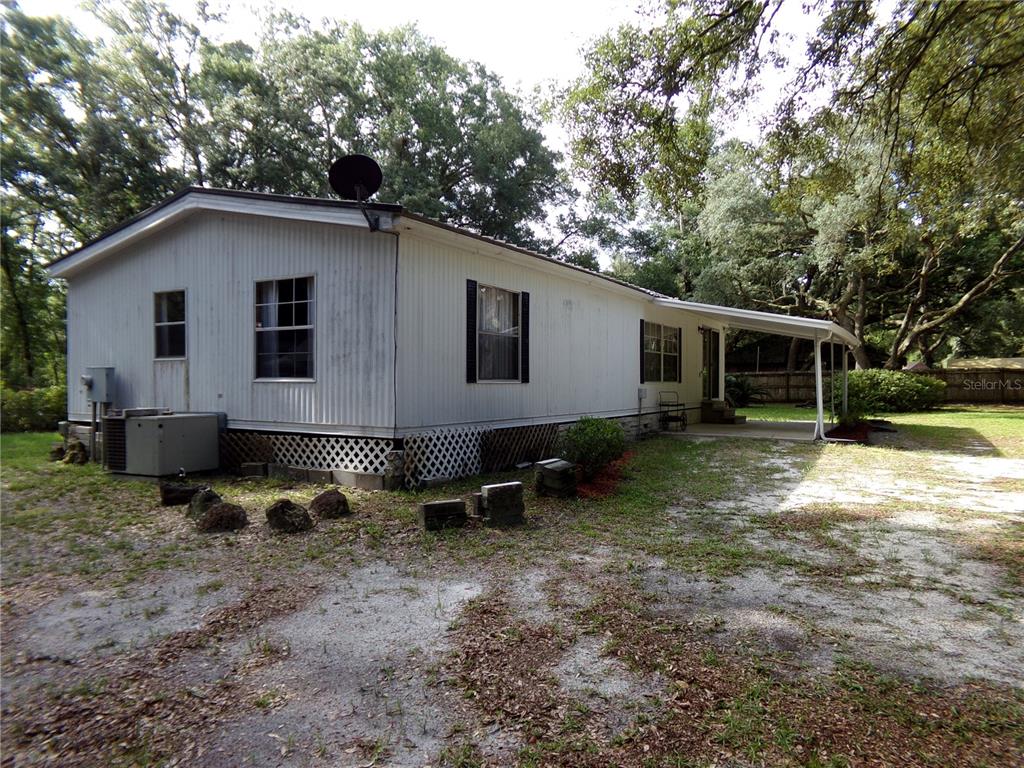 A single-story mobile home with white siding, a carport, and a gravel driveway — 12199 SW 44TH DRIVE, WEBSTER, FL