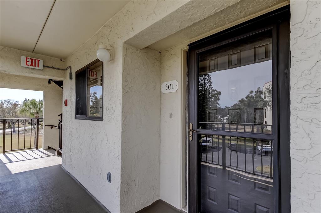 An exterior view of an apartment entrance with a screen door labeled 301 — 9450 HARBOR GREENS WAY UNIT 301, SEMINOLE, FL