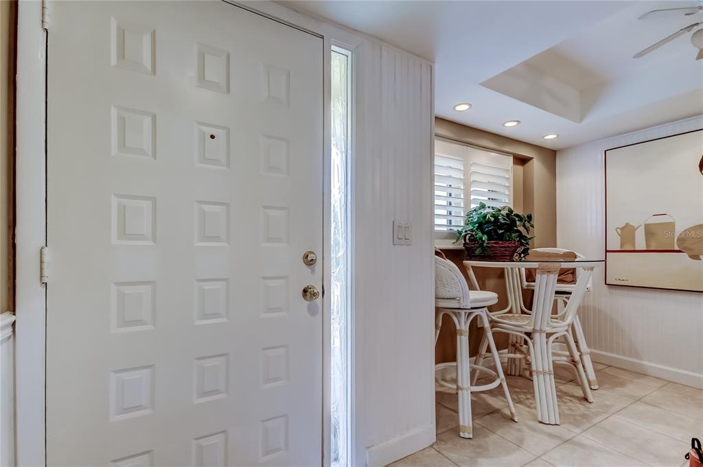 A white front door with a side window opens into a dining area with tile flooring — 9450 HARBOR GREENS WAY UNIT 301, SEMINOLE, FL