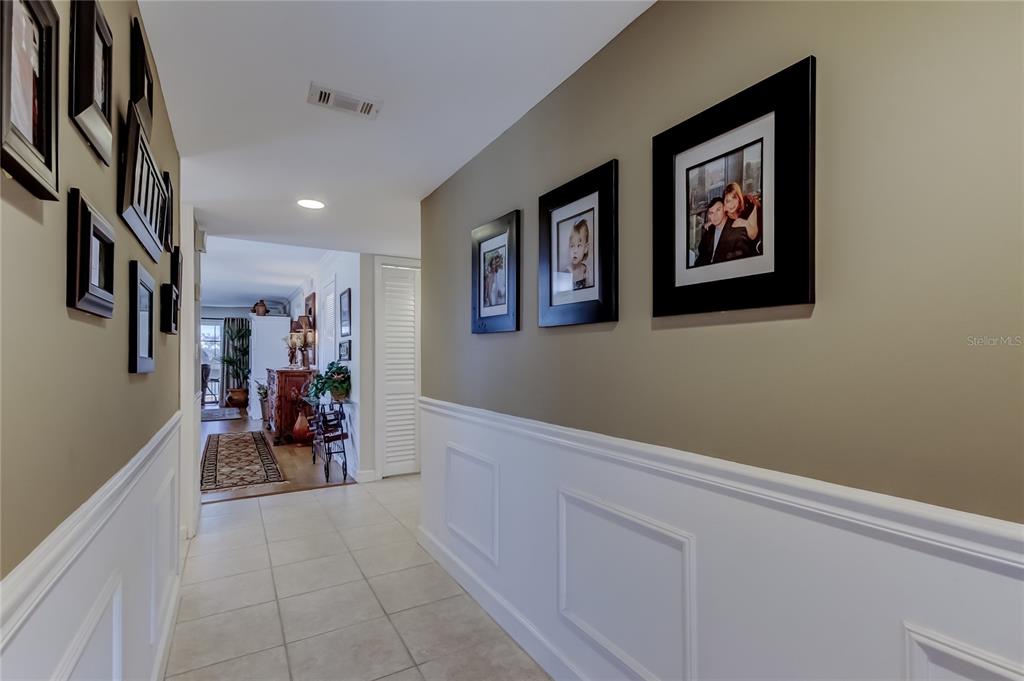 A hallway with tiled floors, white wainscoting, and framed photos on tan walls — 9450 HARBOR GREENS WAY UNIT 301, SEMINOLE, FL