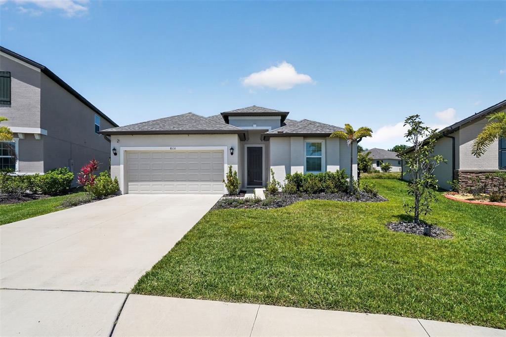 A single-story house with a two-car garage and a front lawn under a blue sky — 8131 TEA OLIVE TERRACE, PALMETTO, FL