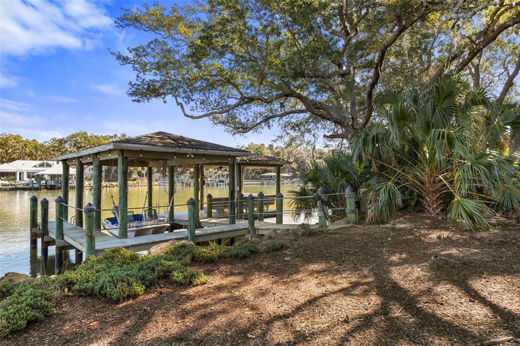 A wooden boat dock with a covered slip sits on a calm waterway near trees — 46 OLD OAK DRIVE S, PALM COAST, FL