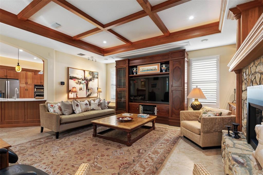 A living room features a coffered wood ceiling, a large media cabinet, and a stone fireplace — 46 OLD OAK DRIVE S, PALM COAST, FL