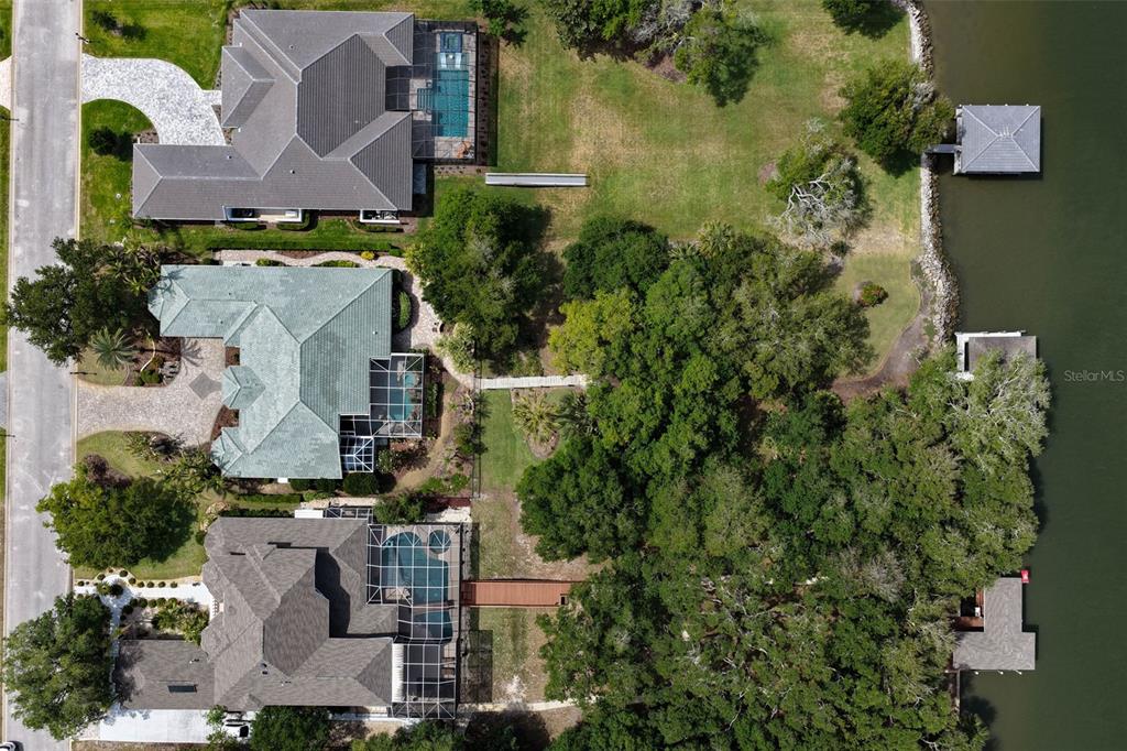 An aerial view shows three waterfront homes with swimming pools and private docks — 46 OLD OAK DRIVE S, PALM COAST, FL
