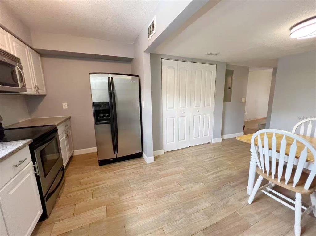 A kitchen with stainless steel appliances, white cabinets, and light wood-look flooring — 14402 REUTER STRASSE CIRCLE UNIT 223, TAMPA, FL