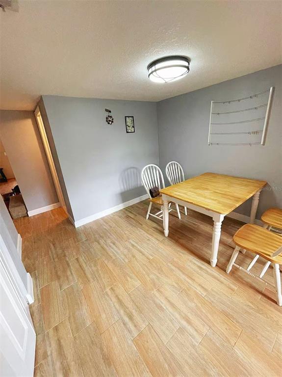 A dining area features a wooden table, three chairs, and light-colored wood-look tile flooring — 14402 REUTER STRASSE CIRCLE UNIT 223, TAMPA, FL