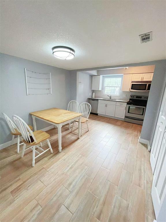 A dining area with a wooden table and chairs sits adjacent to a white kitchen — 14402 REUTER STRASSE CIRCLE UNIT 223, TAMPA, FL