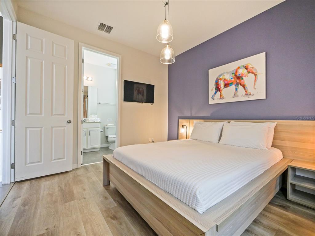 A bedroom features a platform bed, a purple accent wall, and an attached bathroom — 1810 SAWYER PALM PLACE, KISSIMMEE, FL