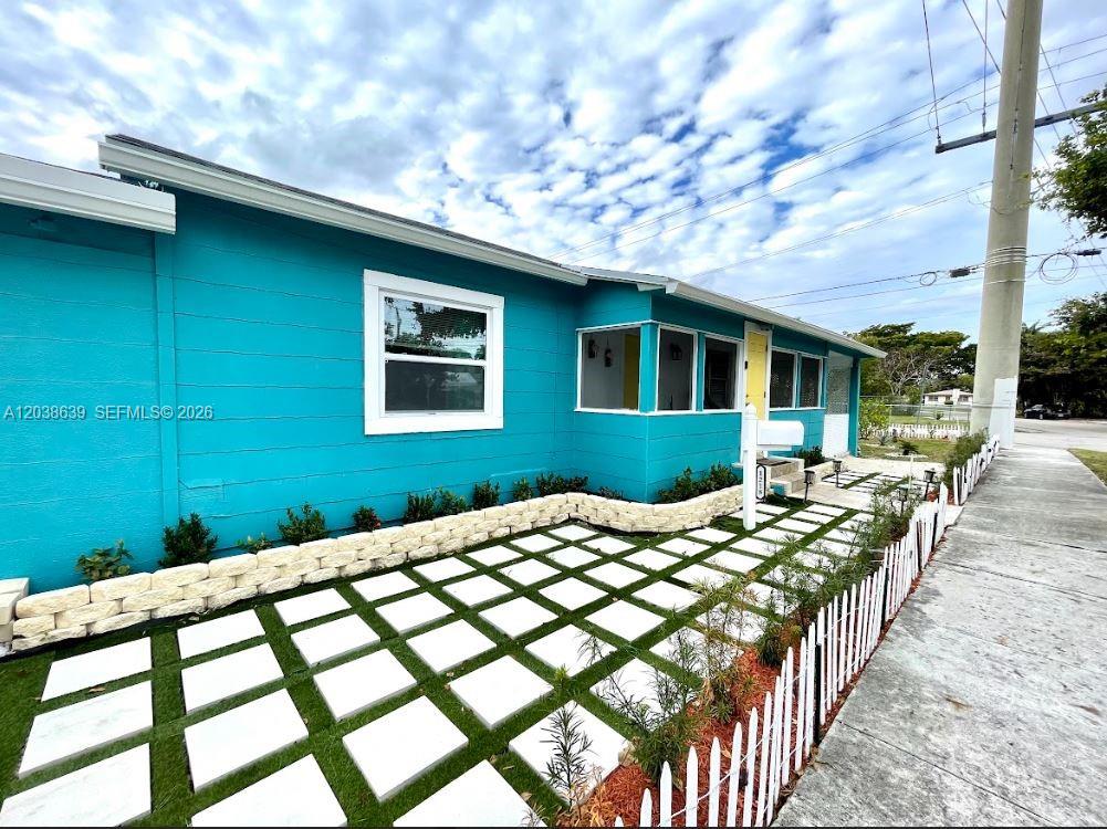 A bright turquoise house features a white picket fence and a grid-patterned paver walkway — 1218 N 24th Ave, Hollywood FL 33020, HOLLYWOOD, FL