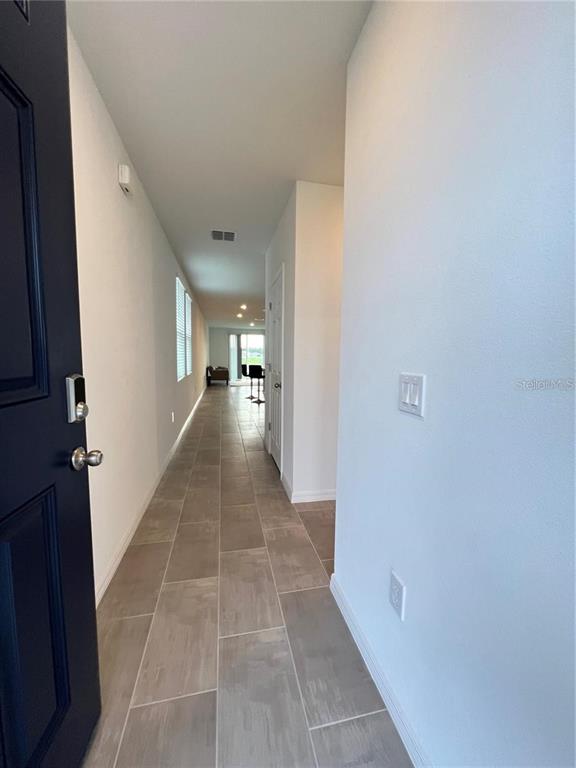 A view from an open front door into a long hallway with light-colored tile flooring — 3079 LAUREL OAK LANE, WINTER HAVEN, FL