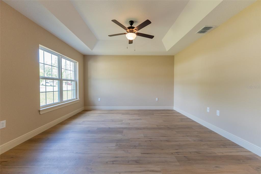 An empty room with light-colored walls, wood-look flooring, and a tray ceiling with a fan — 12233 SW 95TH PLACE, DUNNELLON, FL