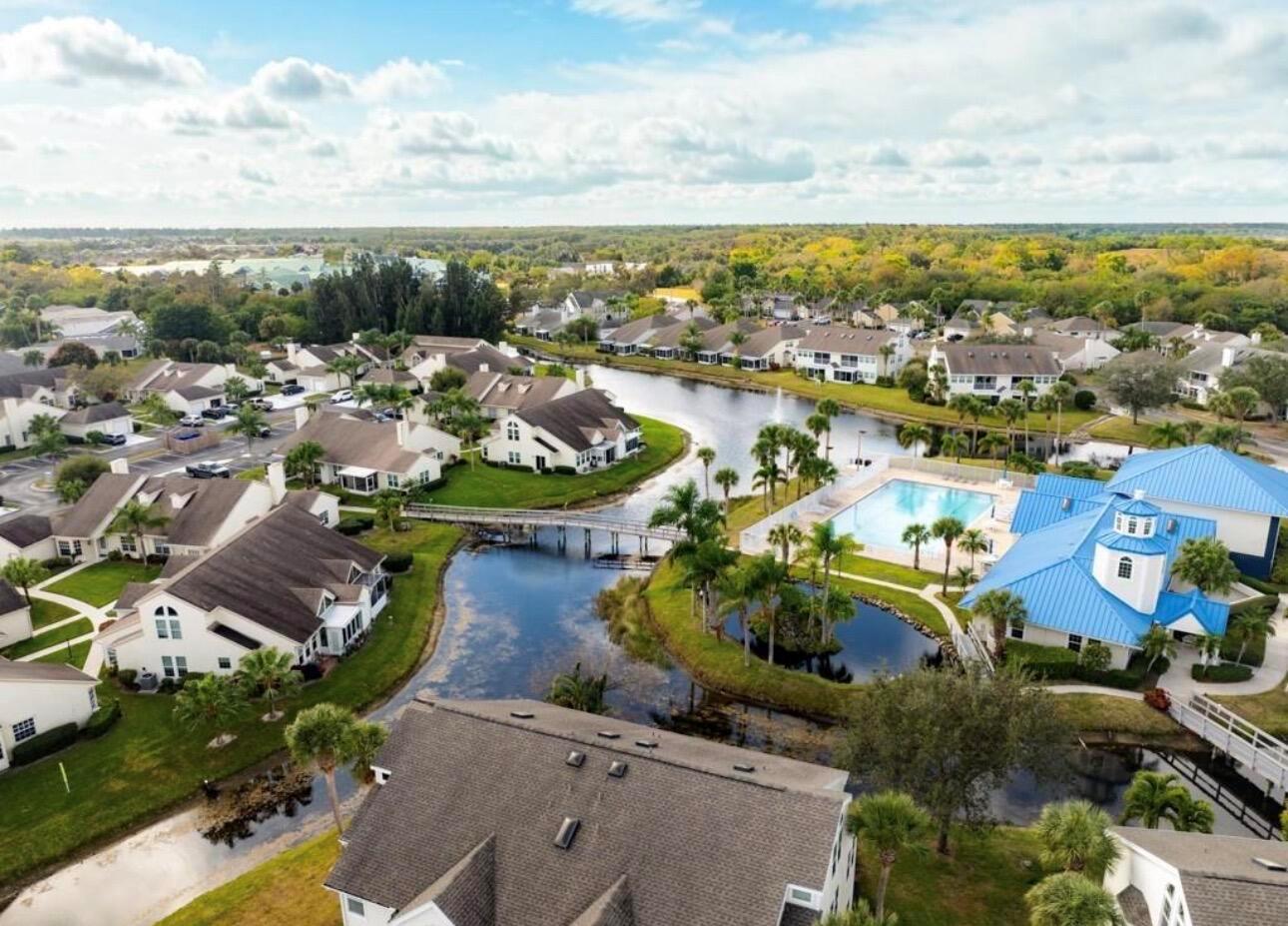 An aerial view of a residential community featuring a swimming pool, pond, and footbridge — 1907 Aynsley Way # 2, Vero Beach FL 32966, VERO BEACH, FL