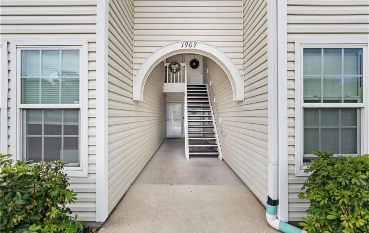An exterior view of a building entrance with stairs leading to an upper level — 1907 Aynsley Way # 2, Vero Beach FL 32966, VERO BEACH, FL