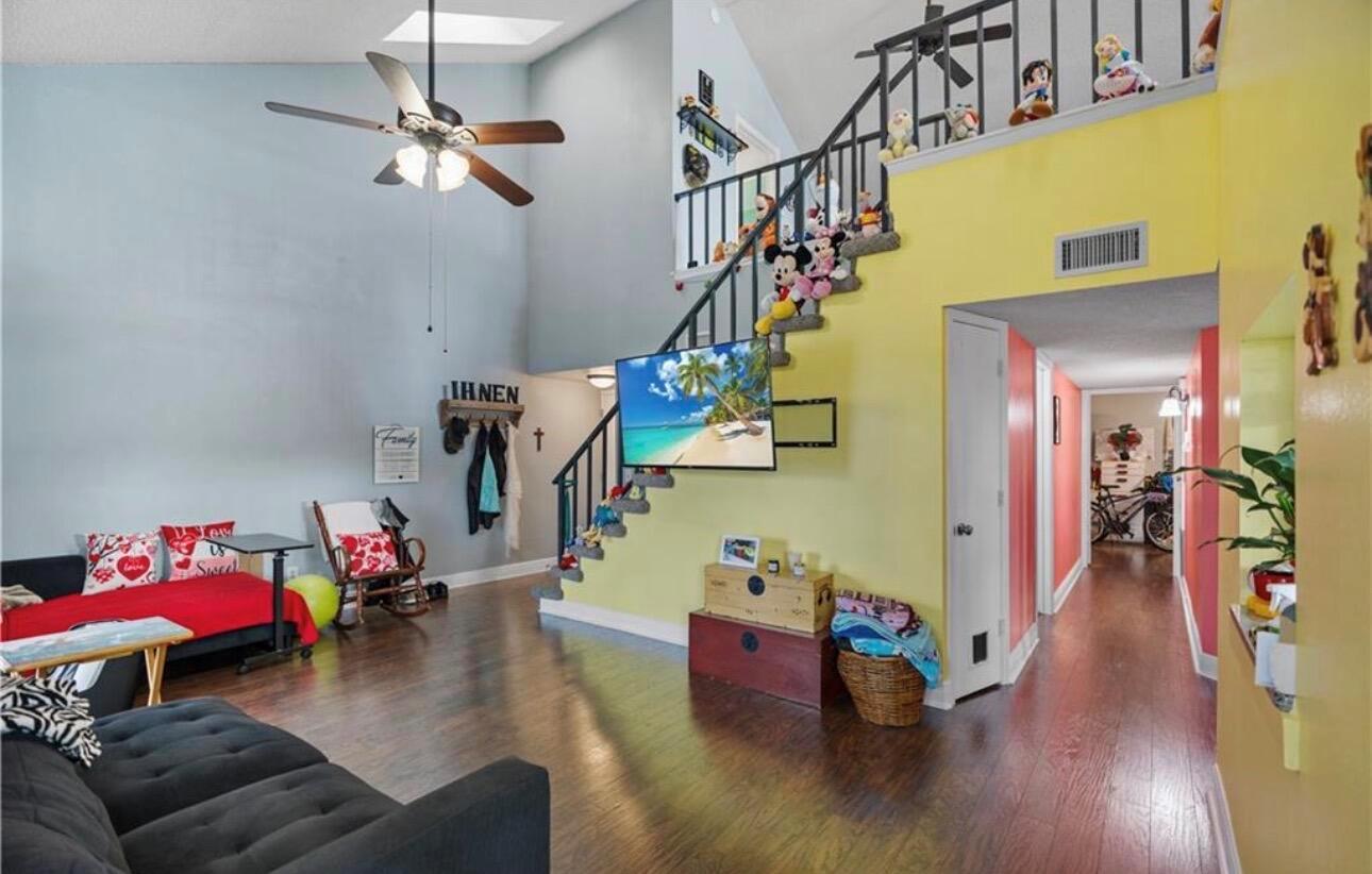A living room with a vaulted ceiling, a staircase, and a wall-mounted television — 1907 Aynsley Way # 2, Vero Beach FL 32966, VERO BEACH, FL