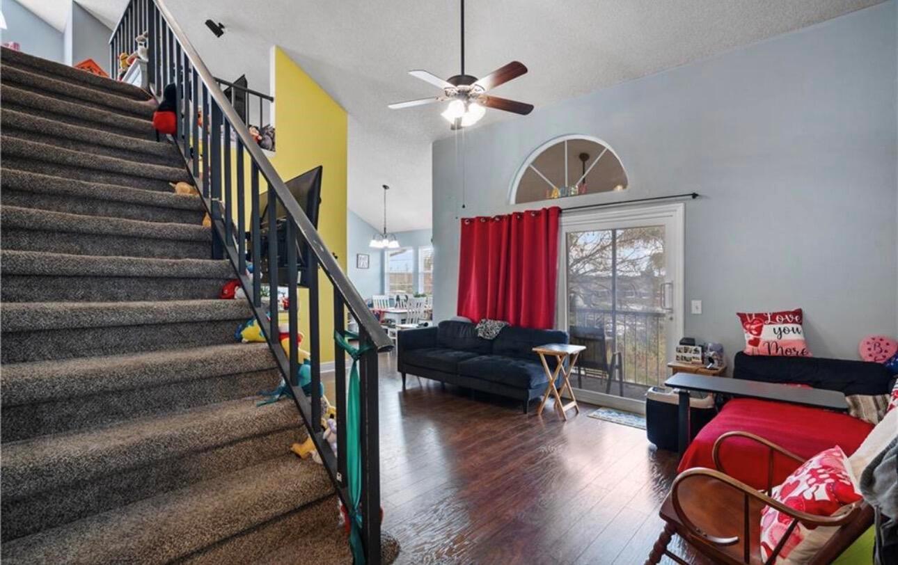 A living room features a carpeted staircase, dark wood flooring, and a sliding glass door — 1907 Aynsley Way # 2, Vero Beach FL 32966, VERO BEACH, FL