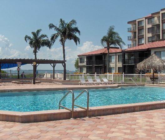 A swimming pool with a metal ladder sits in front of a multi-story apartment building — 6158 PALMA DEL MAR BOULEVARD S UNIT 401, ST PETERSBURG, FL