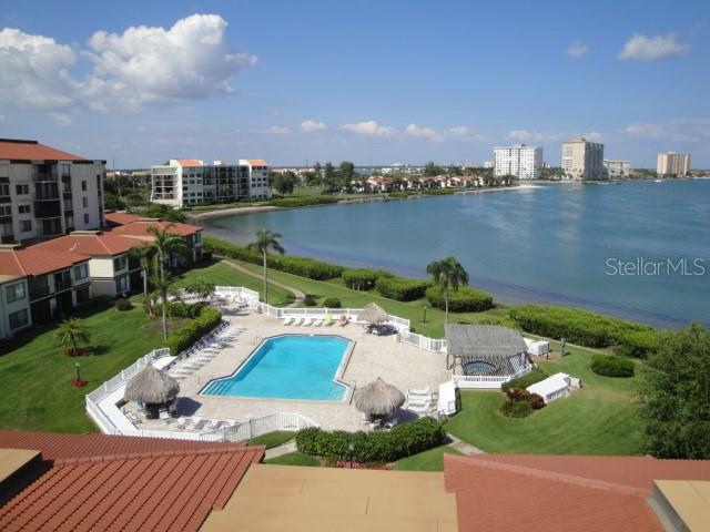 An elevated view shows a swimming pool and patio area surrounded by buildings and water — 6158 PALMA DEL MAR BOULEVARD S UNIT 401, ST PETERSBURG, FL