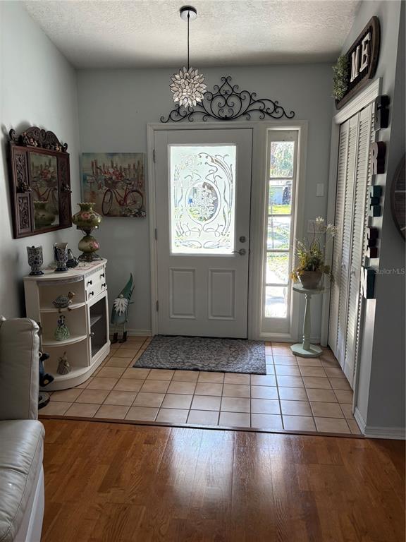 An entryway features a white front door with a glass insert, tile flooring, and decor — 1910 S PARK AVENUE, SANFORD, FL