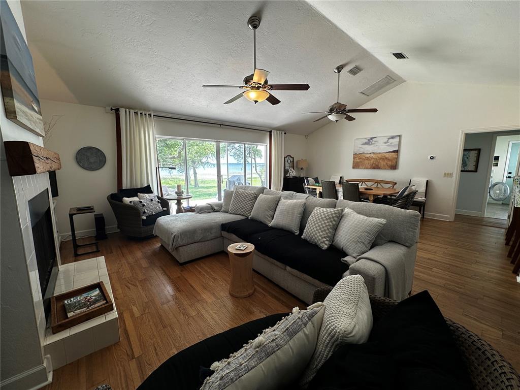 A living room with a sectional sofa, fireplace, and sliding glass doors overlooking a lake — 12595 SE SUNSET HARBOR ROAD, WEIRSDALE, FL