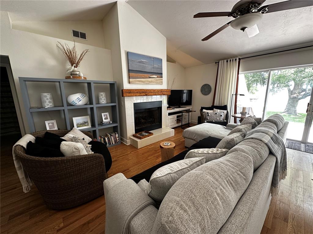 A living room features a fireplace, a large sectional sofa, and a gray bookshelf — 12595 SE SUNSET HARBOR ROAD, WEIRSDALE, FL