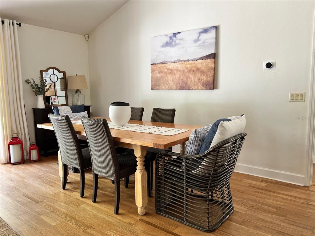 A dining room features a wooden table, upholstered chairs, a wicker armchair, and wall art — 12595 SE SUNSET HARBOR ROAD, WEIRSDALE, FL