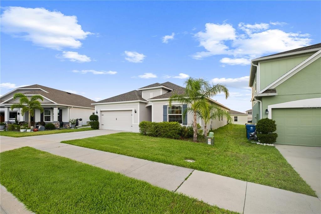 A suburban street view showing three single-family homes with lawns and driveways under a blue sky — 622 TAFT DRIVE, DAVENPORT, FL