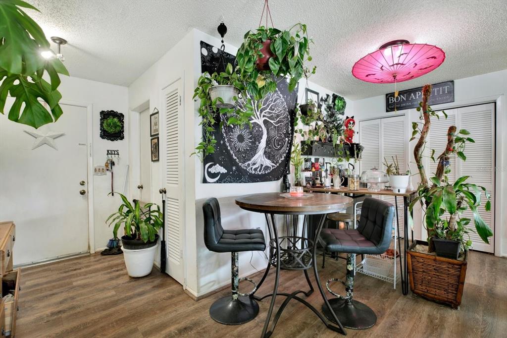 A dining area features a round table, two black stools, and numerous potted plants — 11238 HOLBROOK STREET, SPRING HILL, FL
