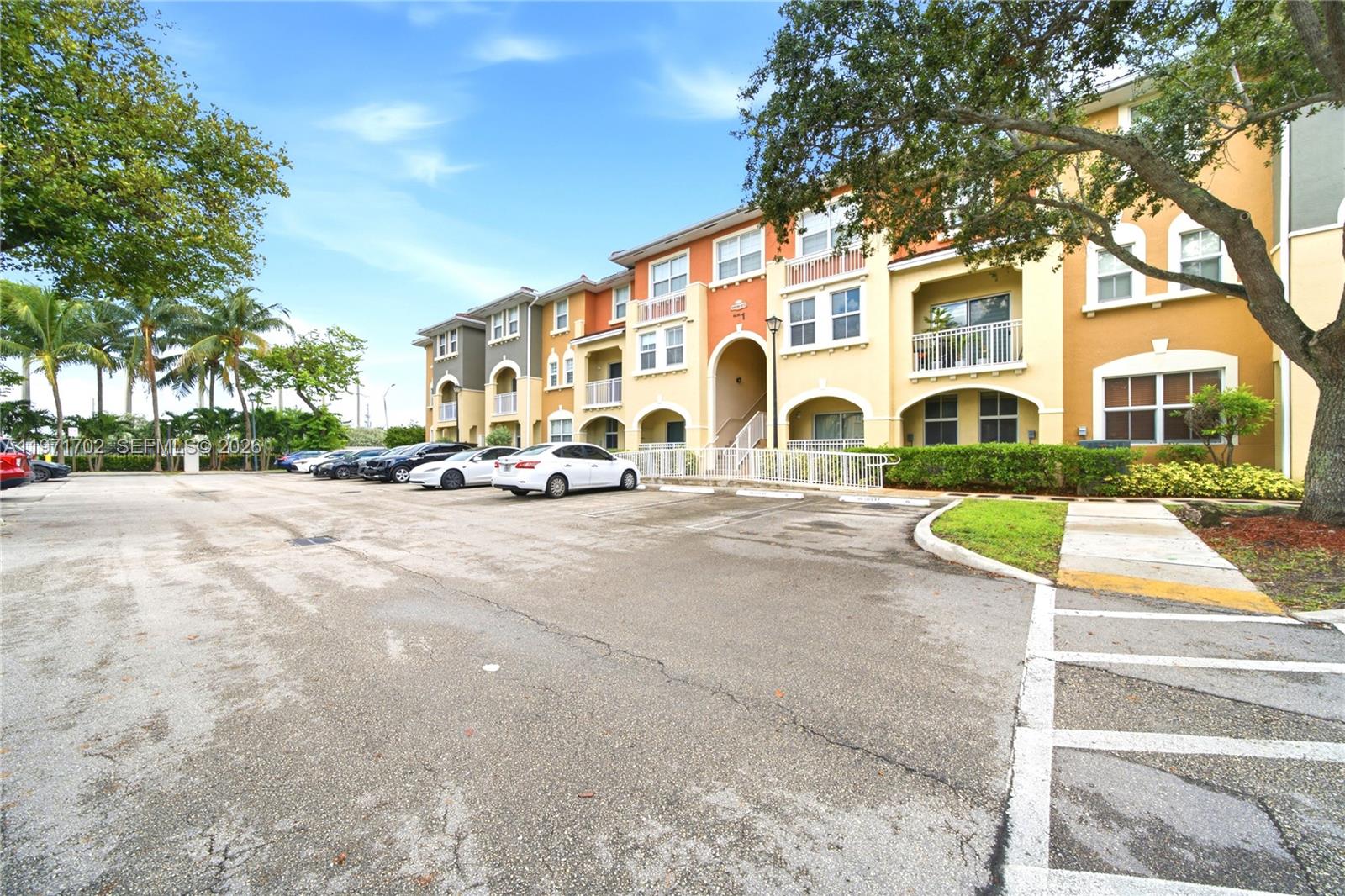 A multi-story apartment building features a parking lot in front with several parked cars — 8999 NW 107th Ct # 1, Doral FL 33178, DORAL, FL