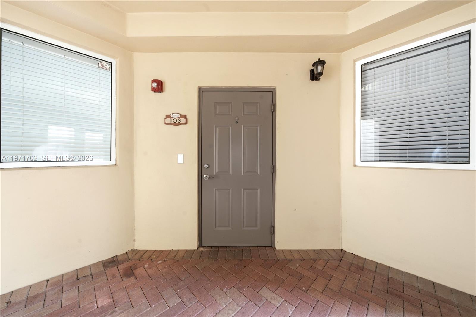 A gray front door is centered between two windows on a brick-paved entryway — 8999 NW 107th Ct # 1, Doral FL 33178, DORAL, FL