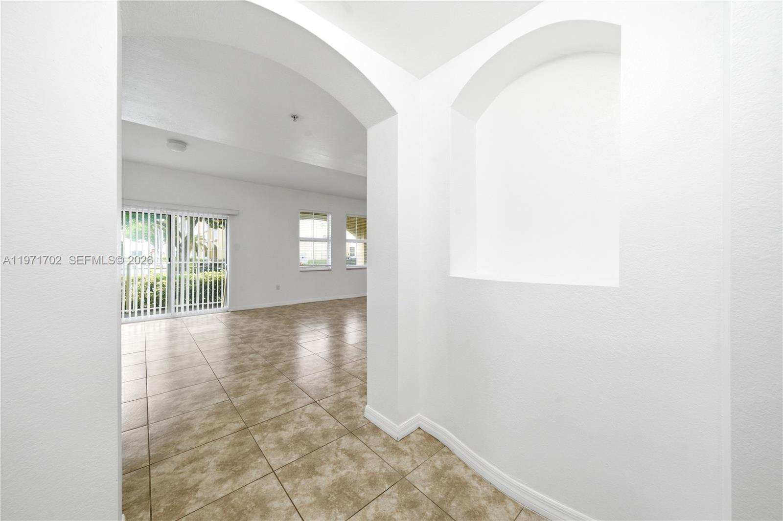 A bright room features tiled floors, an arched entryway, and a recessed wall niche — 8999 NW 107th Ct # 1, Doral FL 33178, DORAL, FL