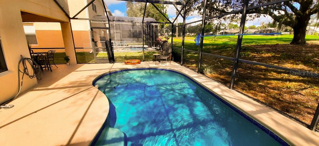 A screened-in patio features a swimming pool and views of a grassy backyard — 1142 MARINER CAY DRIVE, HAINES CITY, FL