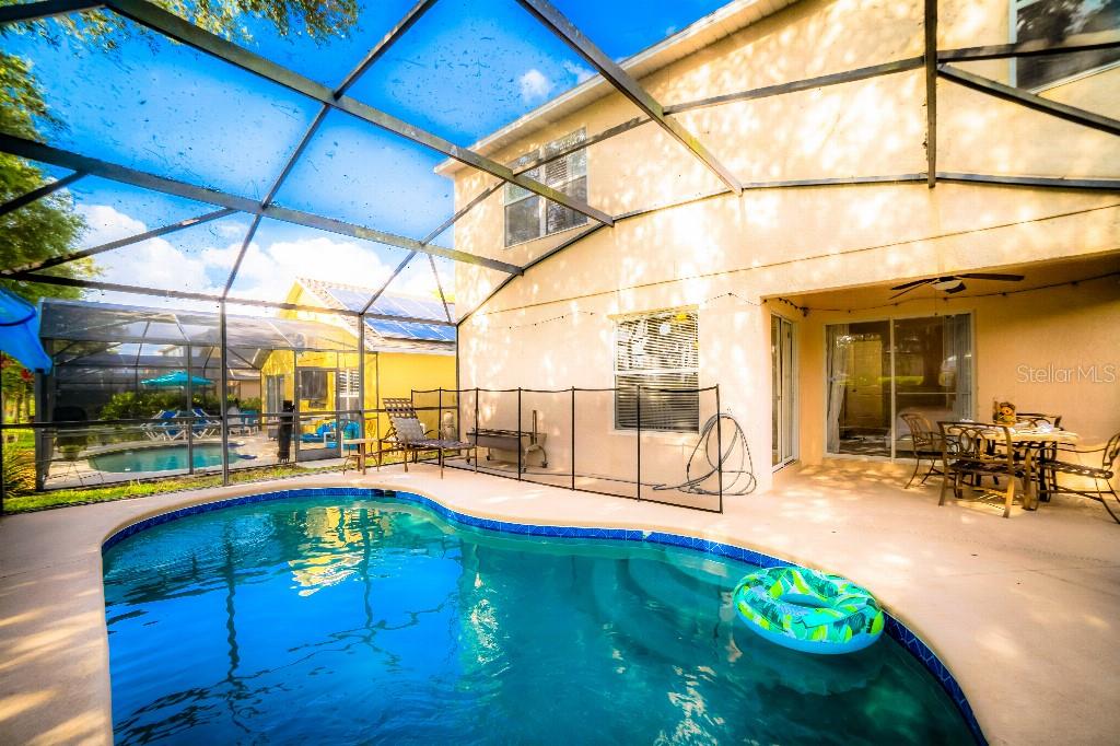 A swimming pool with a screen enclosure sits on the patio of a two-story house — 1142 MARINER CAY DRIVE, HAINES CITY, FL