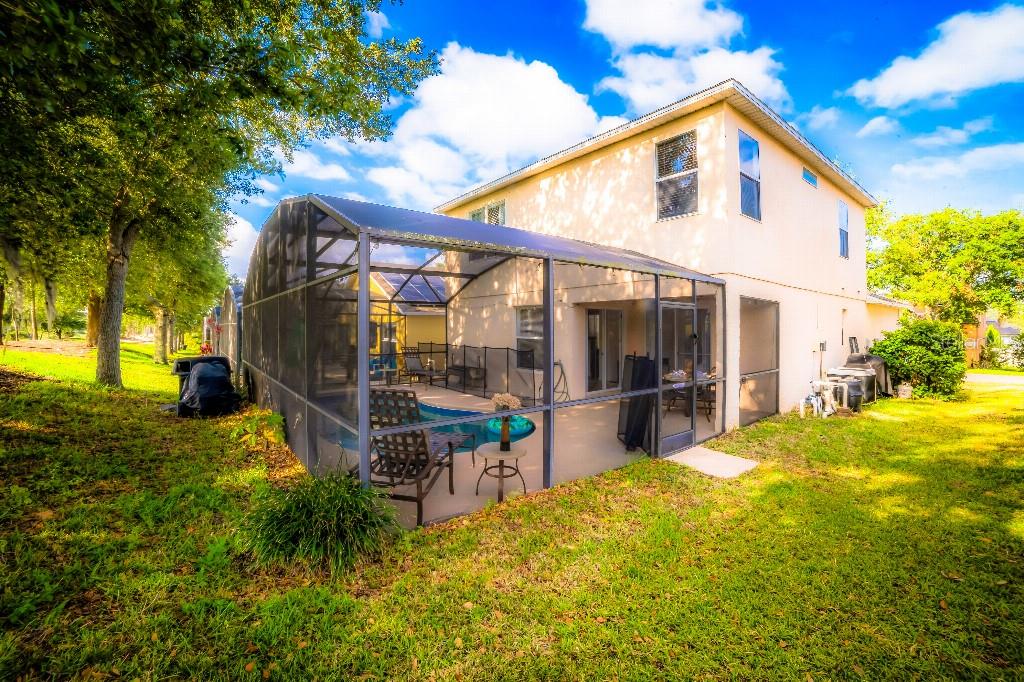 A two-story house with a screened-in pool enclosure and a grassy backyard — 1142 MARINER CAY DRIVE, HAINES CITY, FL