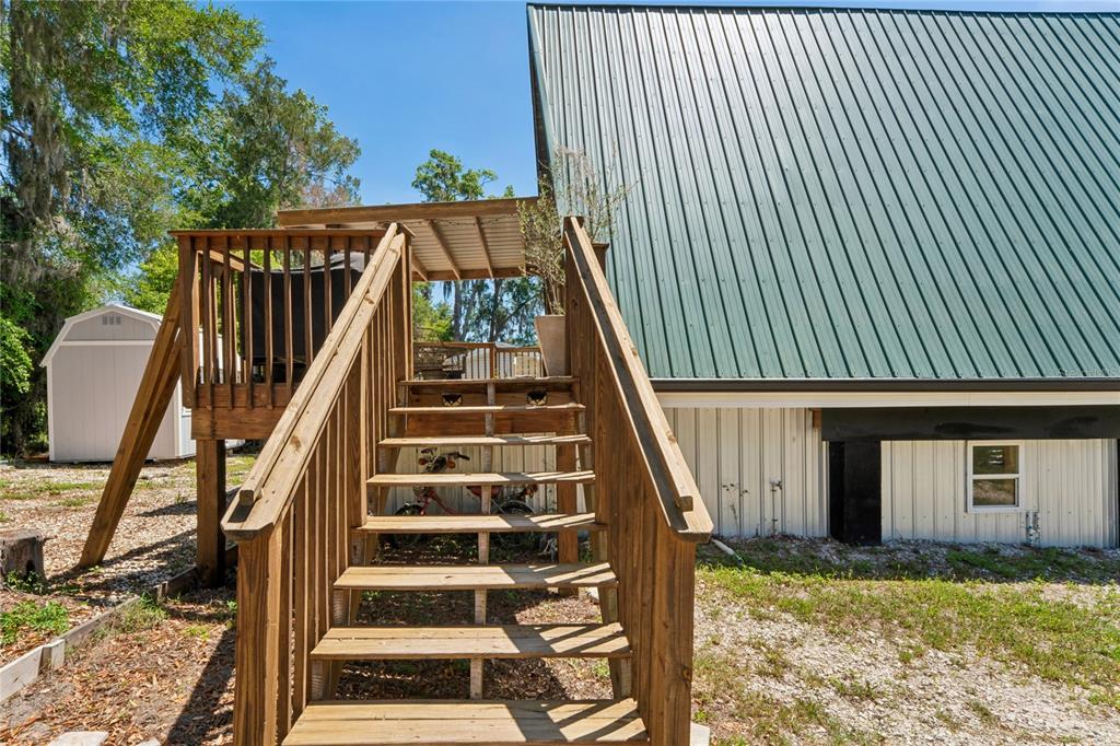 A wooden staircase leads up to a deck attached to a metal-sided building — 9366 CR 649, BUSHNELL, FL