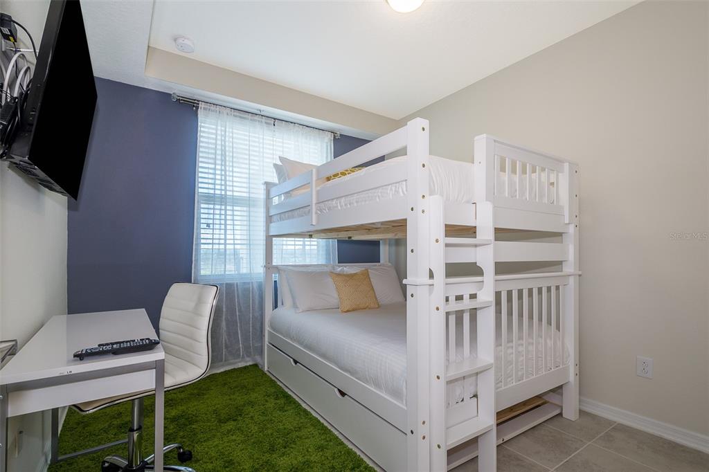 A bedroom features a white bunk bed, a desk with a chair, and green carpeting — 4731 CLOCK TOWER DRIVE UNIT 206, KISSIMMEE, FL