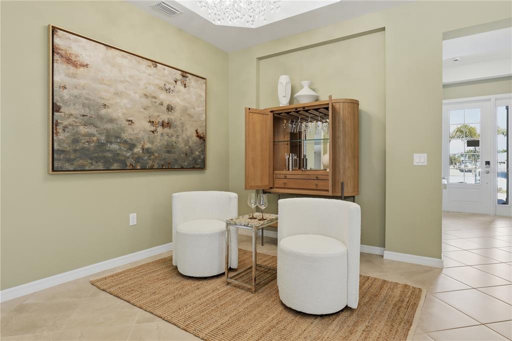 A sitting area features two white chairs, a small table, and a wooden bar cabinet — 19732 TROUT TERRACE, LAKEWOOD RANCH, FL