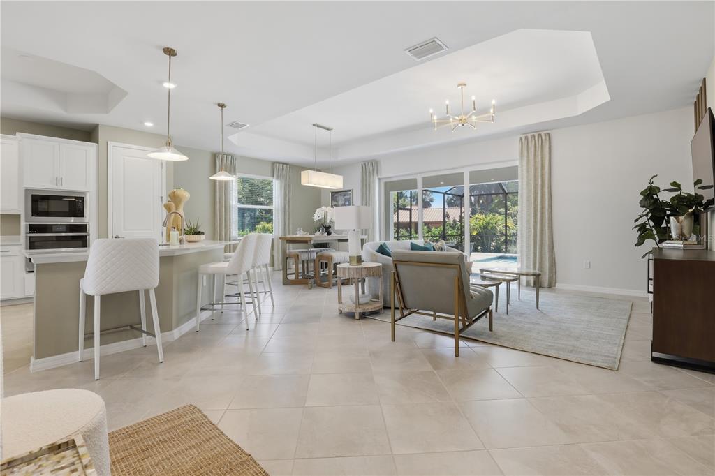 An open-concept kitchen and living area featuring tile floors, white cabinetry, and a pool view — 19732 TROUT TERRACE, LAKEWOOD RANCH, FL