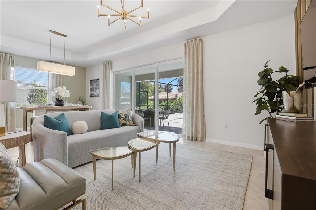 A living room features a grey sofa, nested coffee tables, and sliding doors to a patio — 19732 TROUT TERRACE, LAKEWOOD RANCH, FL