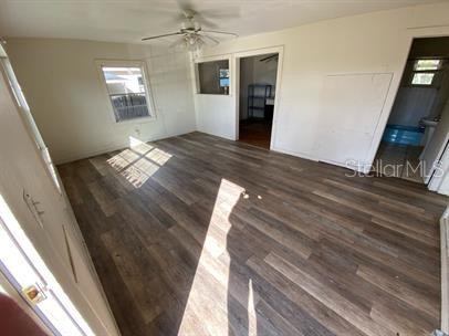 An empty room with wood-look flooring, a ceiling fan, and a doorway leading to a bathroom — 625 HOLMES AVENUE, DAYTONA BEACH, FL