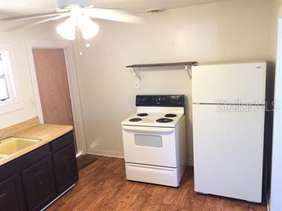 A kitchen features dark cabinets, a white stove, a white refrigerator, and wood-look flooring — 625 HOLMES AVENUE, DAYTONA BEACH, FL