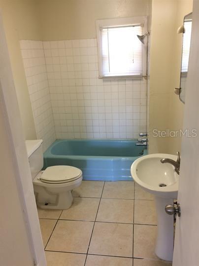 A bathroom features a blue bathtub, a white pedestal sink, a toilet, and tiled flooring — 625 HOLMES AVENUE, DAYTONA BEACH, FL