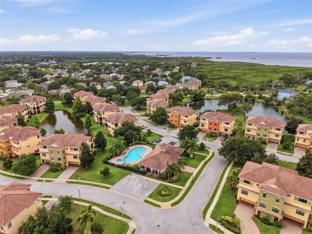 An aerial view of a residential community featuring multi-story buildings, a swimming pool, and ponds — 1532 CITRINE TRAIL, TARPON SPRINGS, FL