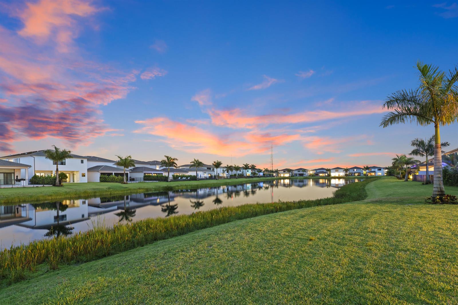 A view of a suburban pond surrounded by houses and palm trees at sunset — 20028 Pacific Dunes Drive, Boca Raton FL 33434, BOCA RATON, FL